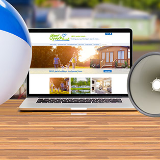 A beach ball and loudhaler sit next to a laptop with the Your Parks website